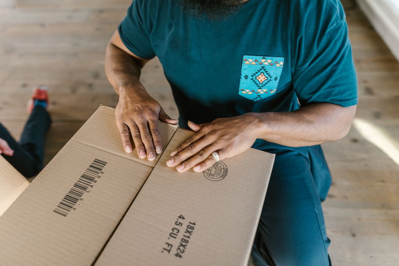 Hands closing a product shipping carton
