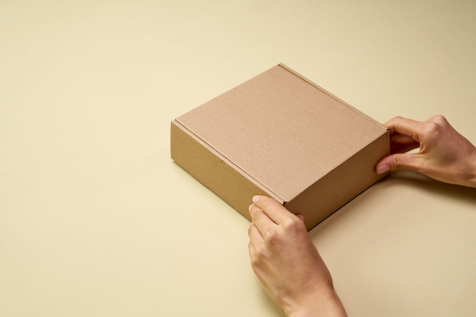 Hands preparing a plain product parcel for dispatch